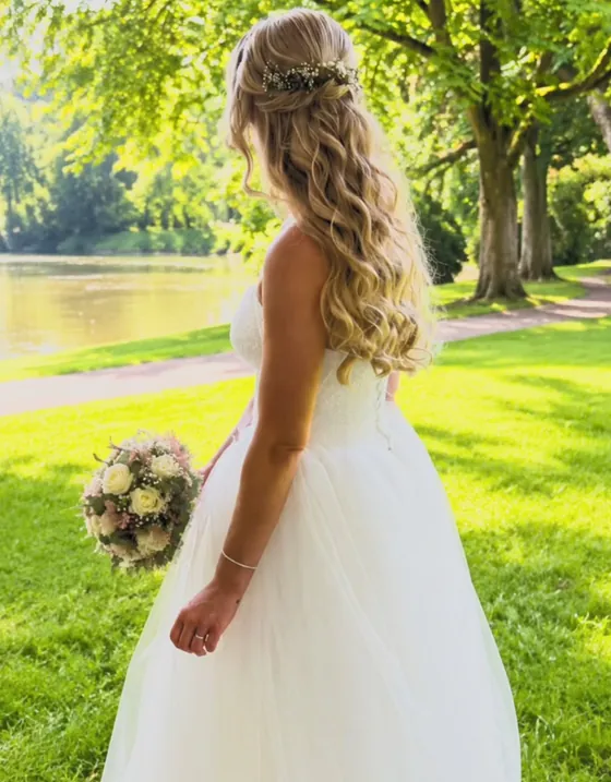 Brautfrisur mit eingeflochtenem Haar und Blumenschmuck