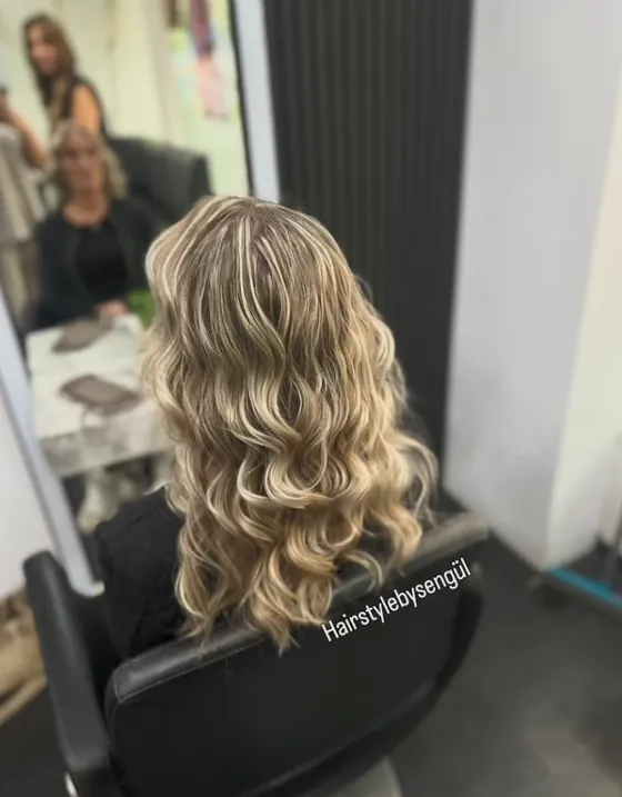 Blonde Locken vor der Salonwand