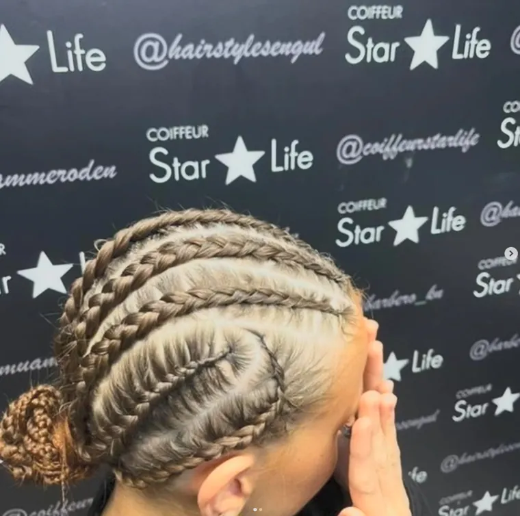 Eng geflochtene Cornrows vor der Salonwand, Coiffeur Star Life Merkstein
